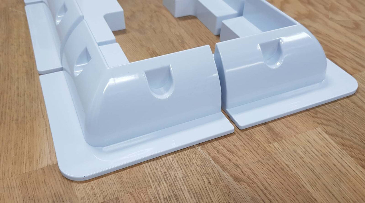 Close-up of white ABS plastic corner brackets showing aerodynamic curved shape and recessed mounting sections