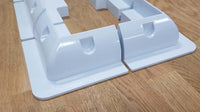 Close-up of white ABS plastic corner brackets showing aerodynamic curved shape and recessed mounting sections