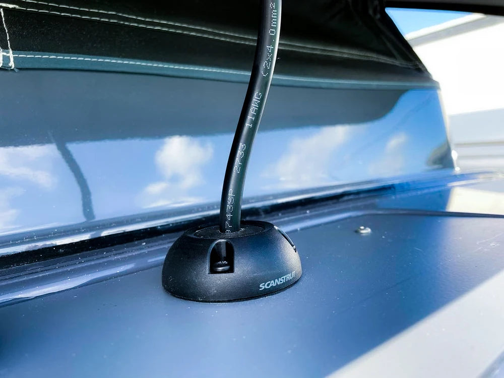 Close-up of a black cable seal installed on a vehicle roof with a thick cable exiting vertically