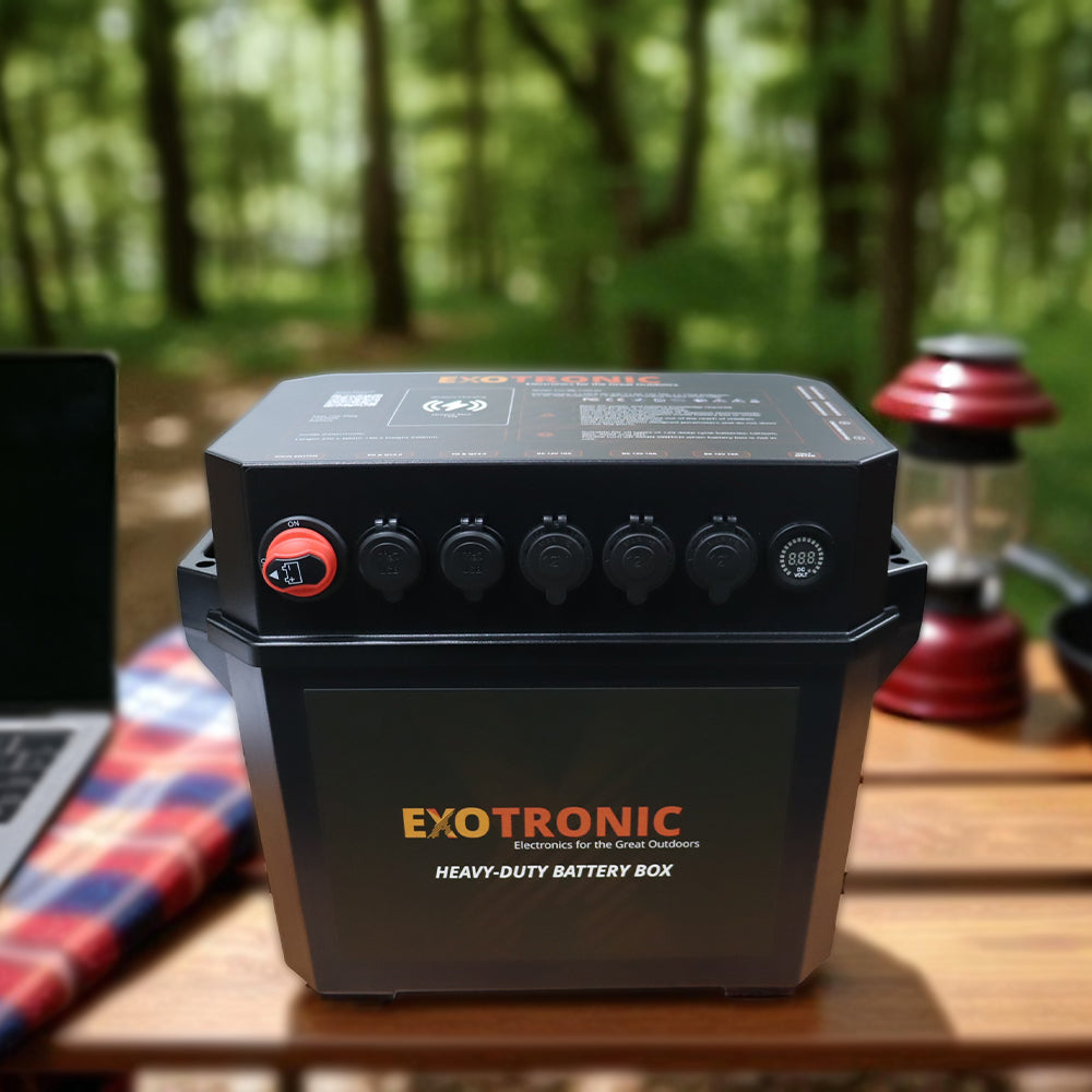 Exotronic battery box sitting on a wooden table in a forest camping environment