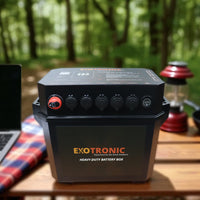 Exotronic battery box sitting on a wooden table in a forest camping environment