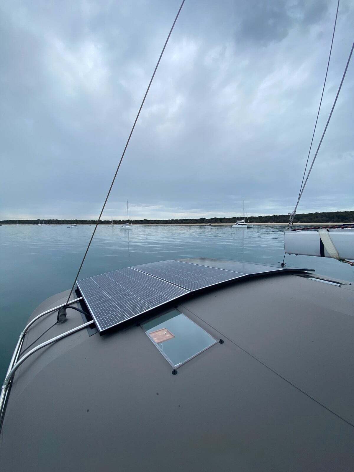 Two fixed solar panels mounted on the curved forward roof of a catamaran