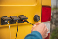 Person connecting an XT60 cable to a Scanstrut solar input socket on a van exterior
