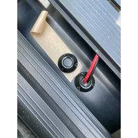 Two black cable seals being installed on a van roof showing cable routing