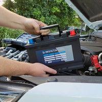 Mechanic lowering the lightweight Invicta lithium battery into a vehicle engine bay