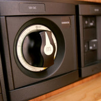 Battery switch integrated into a black marine 12V DC electrical distribution panel