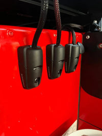 Three black cable seals mounted vertically on a red panel for clean cable management