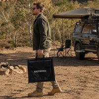 Man carrying the compact folded 300W solar blanket at a remote campsite