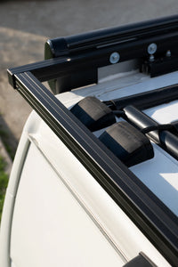 Two cable seals installed on a white van roof near a black roof rack