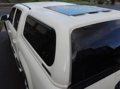 black flexible solar panel with junction box underneath on ute