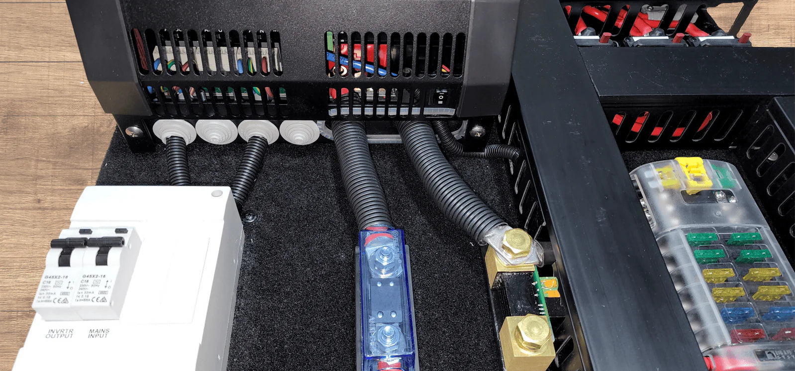 Detail view of the white AC consumer unit and cable routing at the bottom of the board