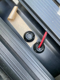 Two black cable seals being installed on a van roof showing cable routing