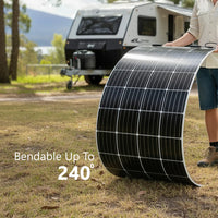 A person holding a flexible solar panel bent into an arc in front of a caravan