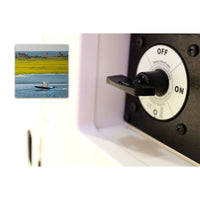 Battery switch installed on a marine vessel dashboard with a boat in the background