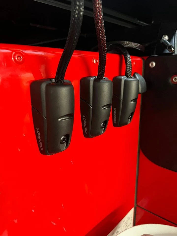 Three black cable seals mounted vertically on a red panel for clean cable management