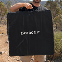Man carrying the folded 200W solar panel in its bag through an outdoor bush setting
