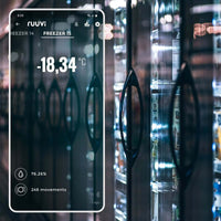 Smartphone displaying Ruuvi app dashboard with temperature reading of minus 18 degrees in front of commercial freezer