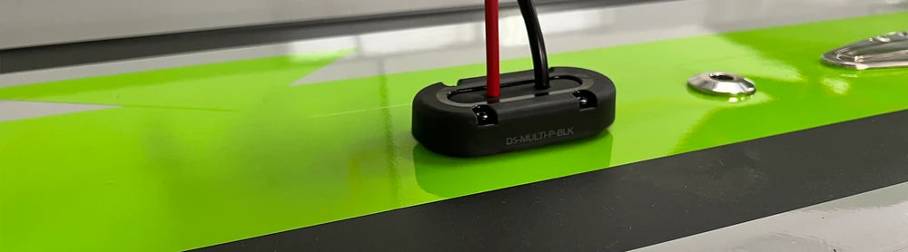 Cable seal installed on a glossy surface with black and red wiring