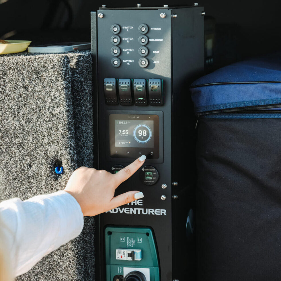 Close-up of a hand operating the Simarine touch screen battery monitor in a canopy