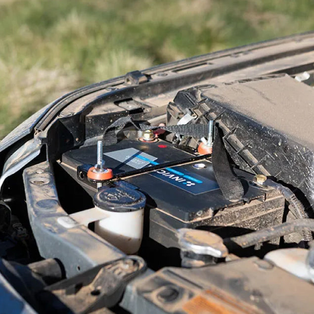 Invicta lithium battery installed in a dusty vehicle engine bay with connected terminals