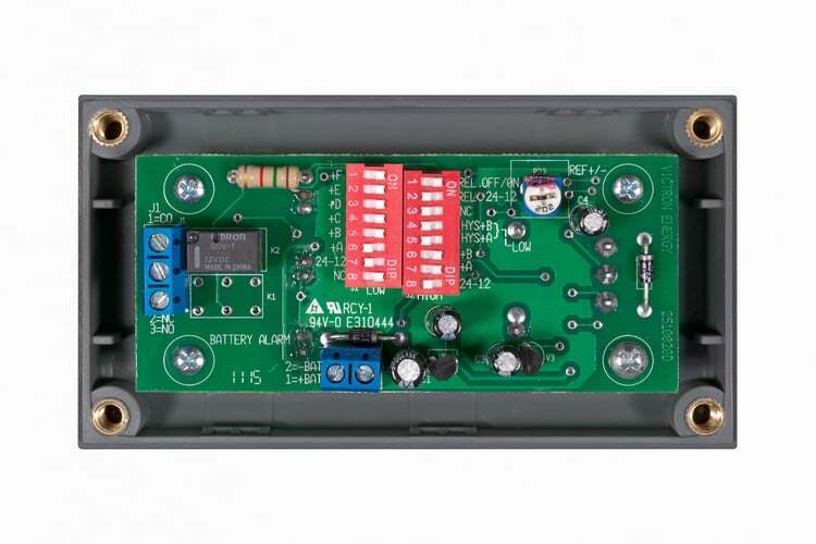 Internal view of battery alarm showing PCB with DIP switches and terminal blocks