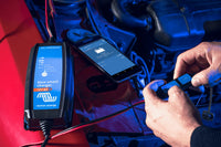 Smartphone displaying VictronConnect app status screen next to the IP65 battery charger