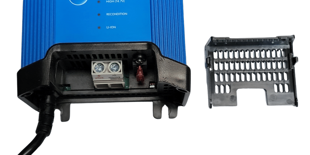 Close-up of battery charger terminals with protective cover removed revealing the internal fuse